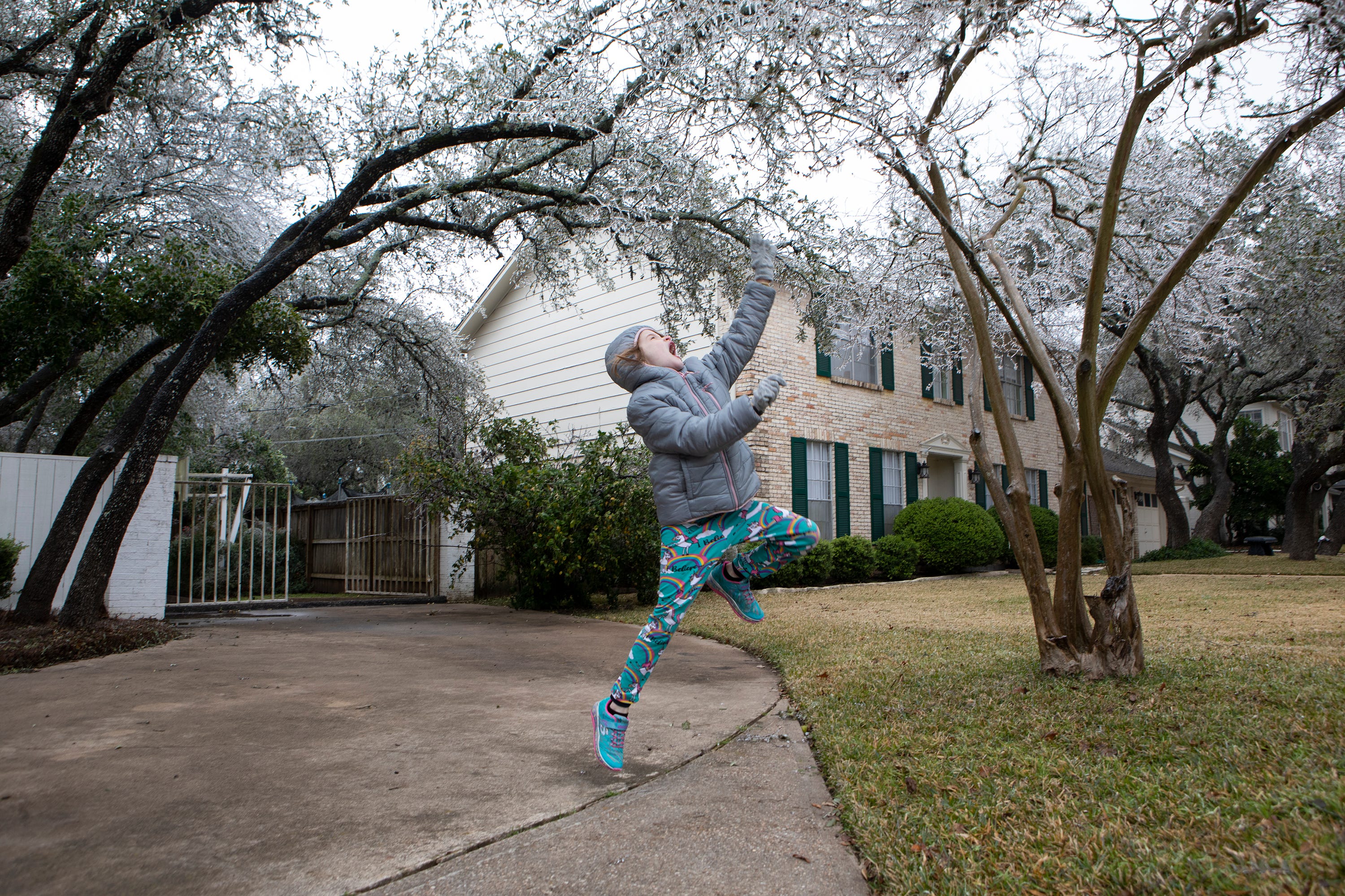 Micah Thomas, 8, jumps for an icicle on Feb. 12, 2021. Icy weather is expected through Sunday.