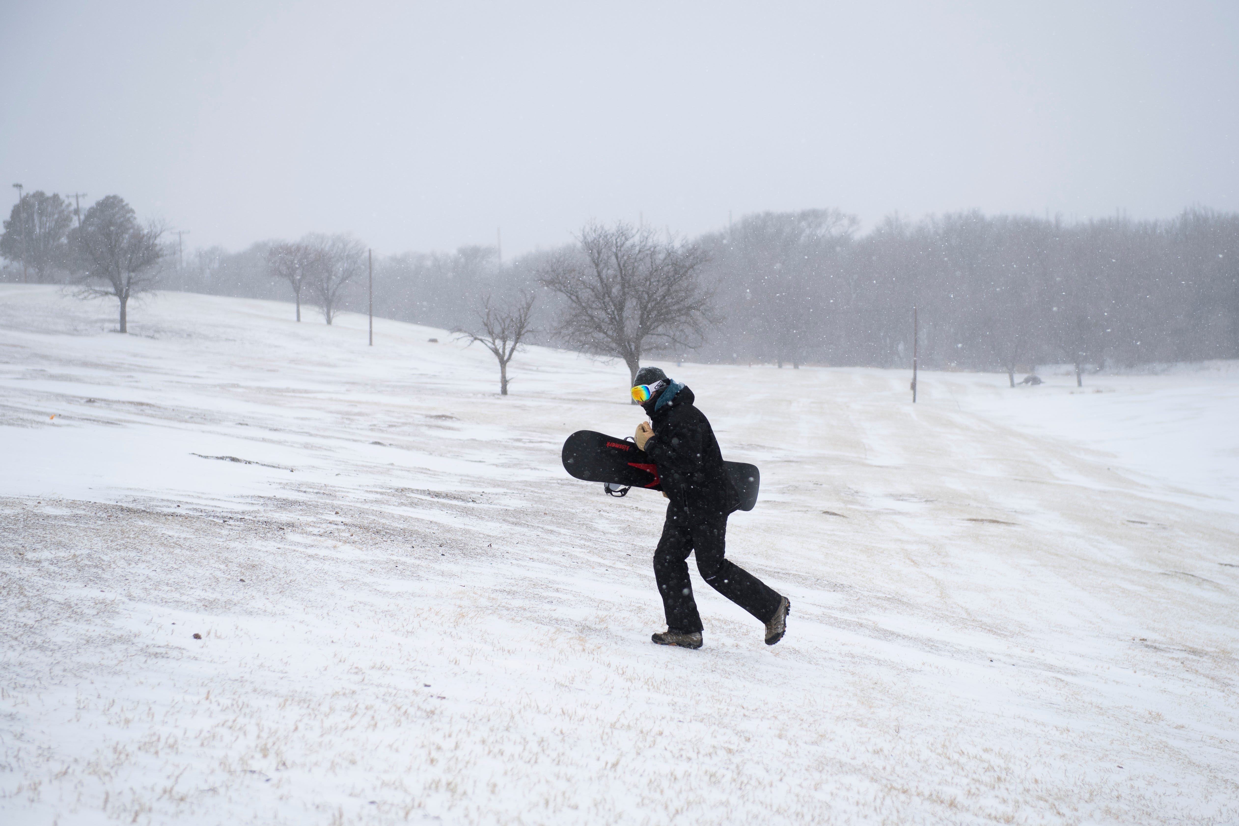 Nick Kuehn hike up a hill after snowboarding down it in Mae Simmons Park on Sunday, Feb. 14, 2021, in Lubbock, Texas.