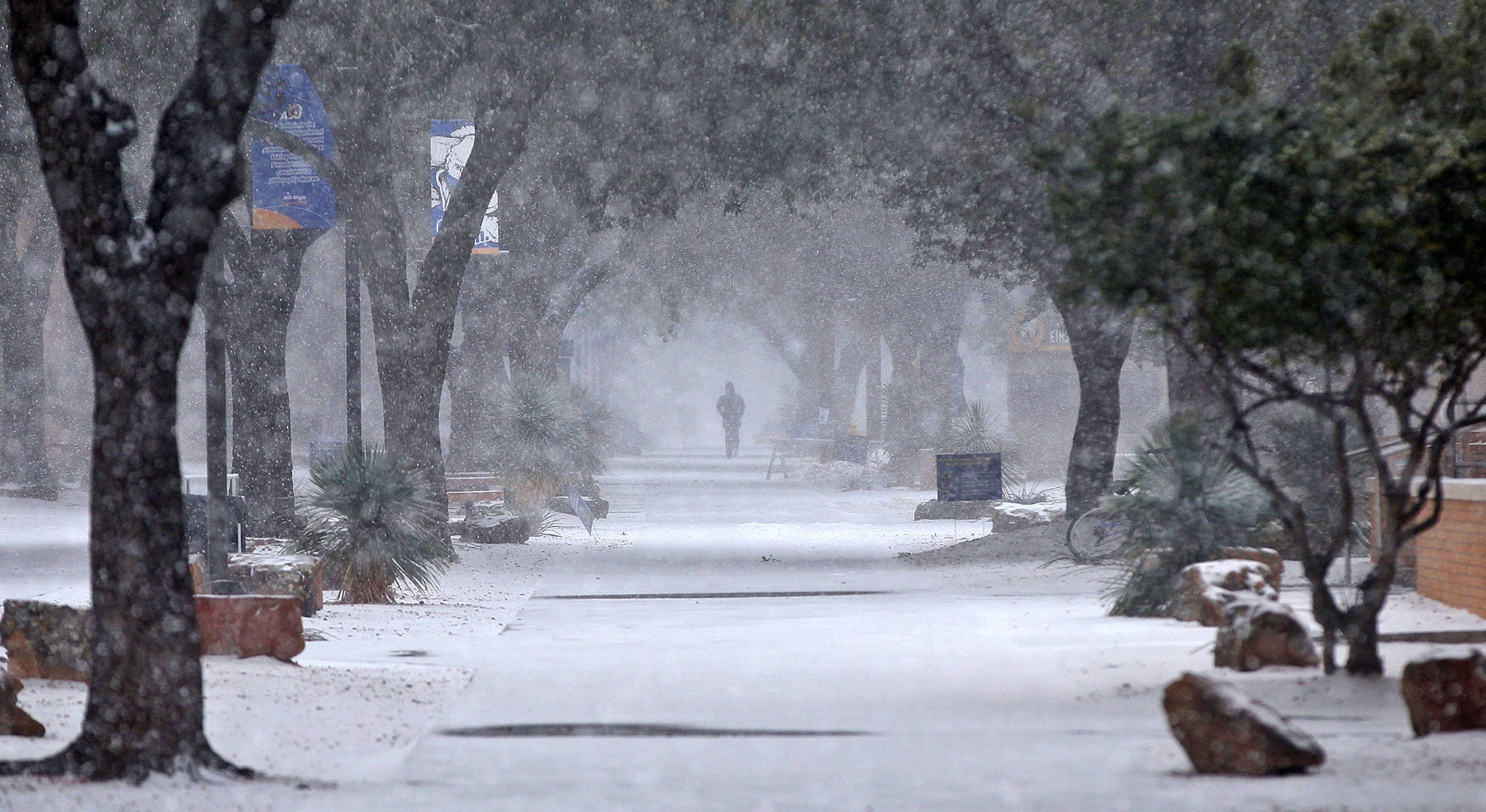 A pedestrian walks through the snow on the Angelo State University campus Sunday, Feb. 14, 2021.