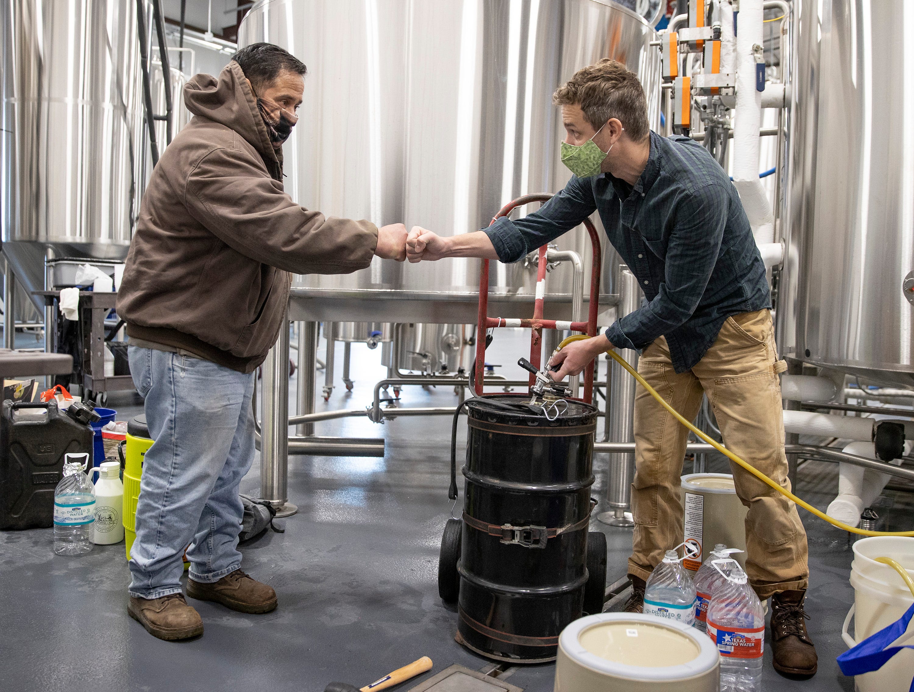Will Jaquiss, right, the owner of Meanwhile Brewing Co., fills a container with water for Victor Perez on Friday during a citywide boil water notice. The brewery in Southeast Austin gave away all 4,000 gallons of their water to people in need on Thursday and Friday.