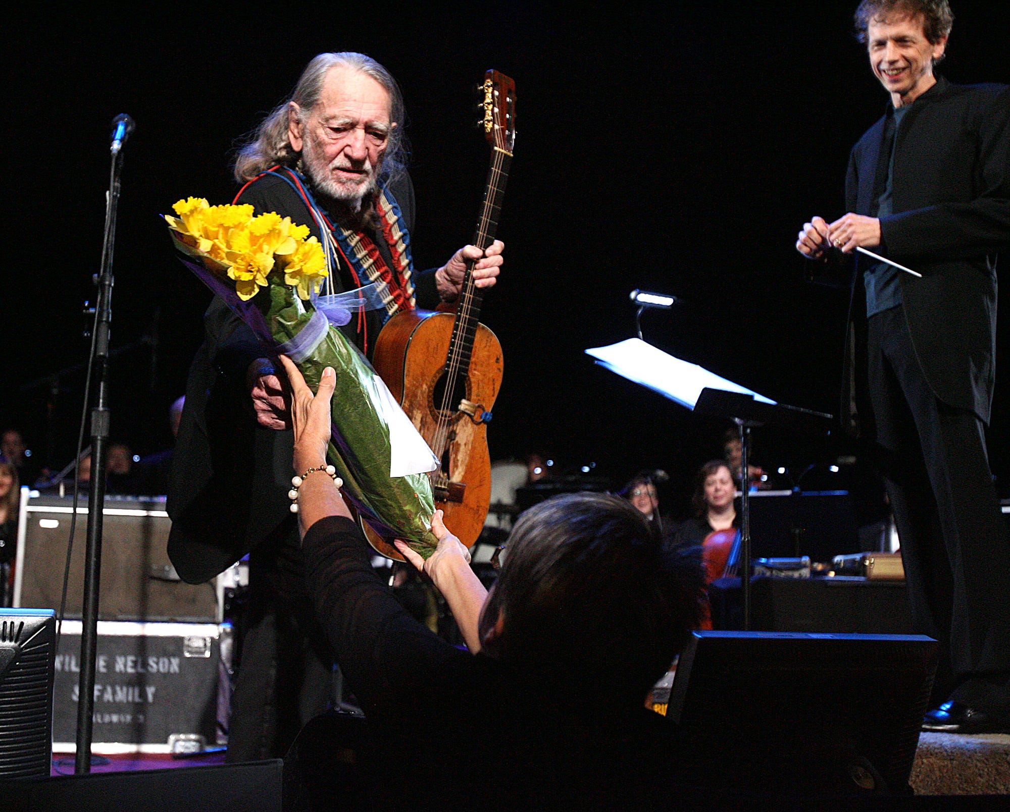 A woman from the audience hands Willie Nelson a bouquet of flowers just before he began playing on February 13, 2011. Nelson and the Austin Symphony christened the new Austin City Limits studio at the W Hotel.