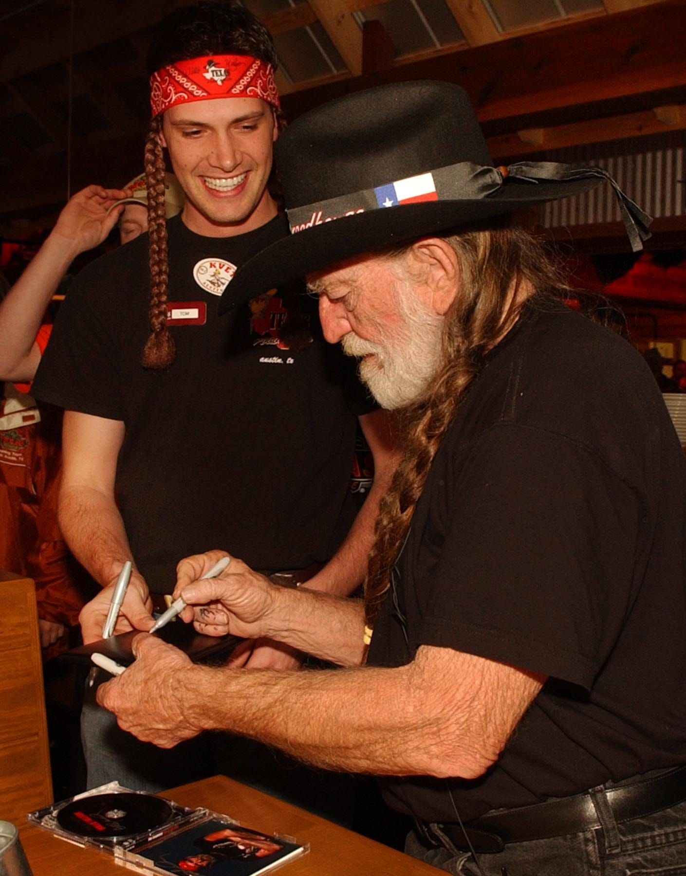 Server Tom Slater (left) gets an autograph from country music legend Willie Nelson at the grand opening of Nelson's Texas Roadhouse restaurant on Thursday Dec. 16, 2004.