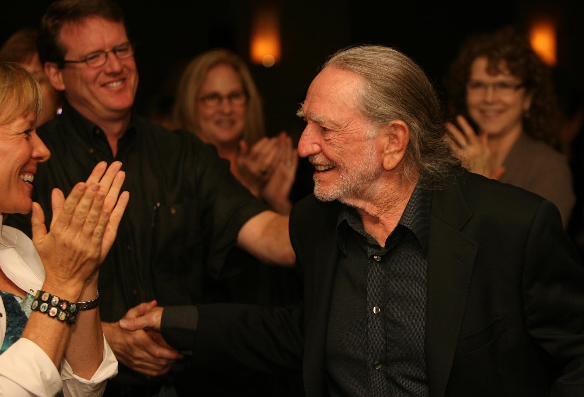 Willie Nelson is congratulated as he walks up to accept the Bridging Divides Award from UT's Project on Conflict Resolution at the Frank Erwin Center on Friday Oct. 19, 2007.
