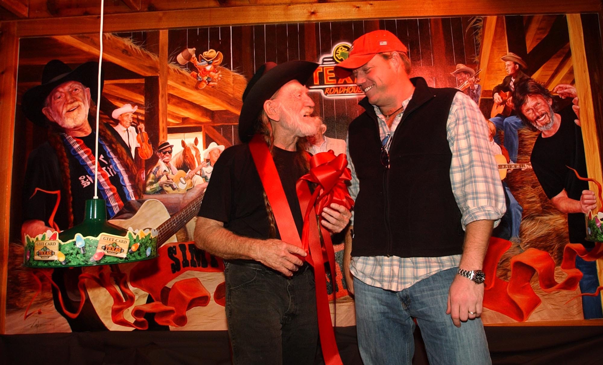 Country music legend Willie Nelson (left) and singer Pat Green visit in front a a mural of country superstars (Green is not in the mural) at the grand opening of Willie Nelson's Texas Roadhouse restaurant on Thursday Dec. 16, 2004.  The mural was created by David Carter.